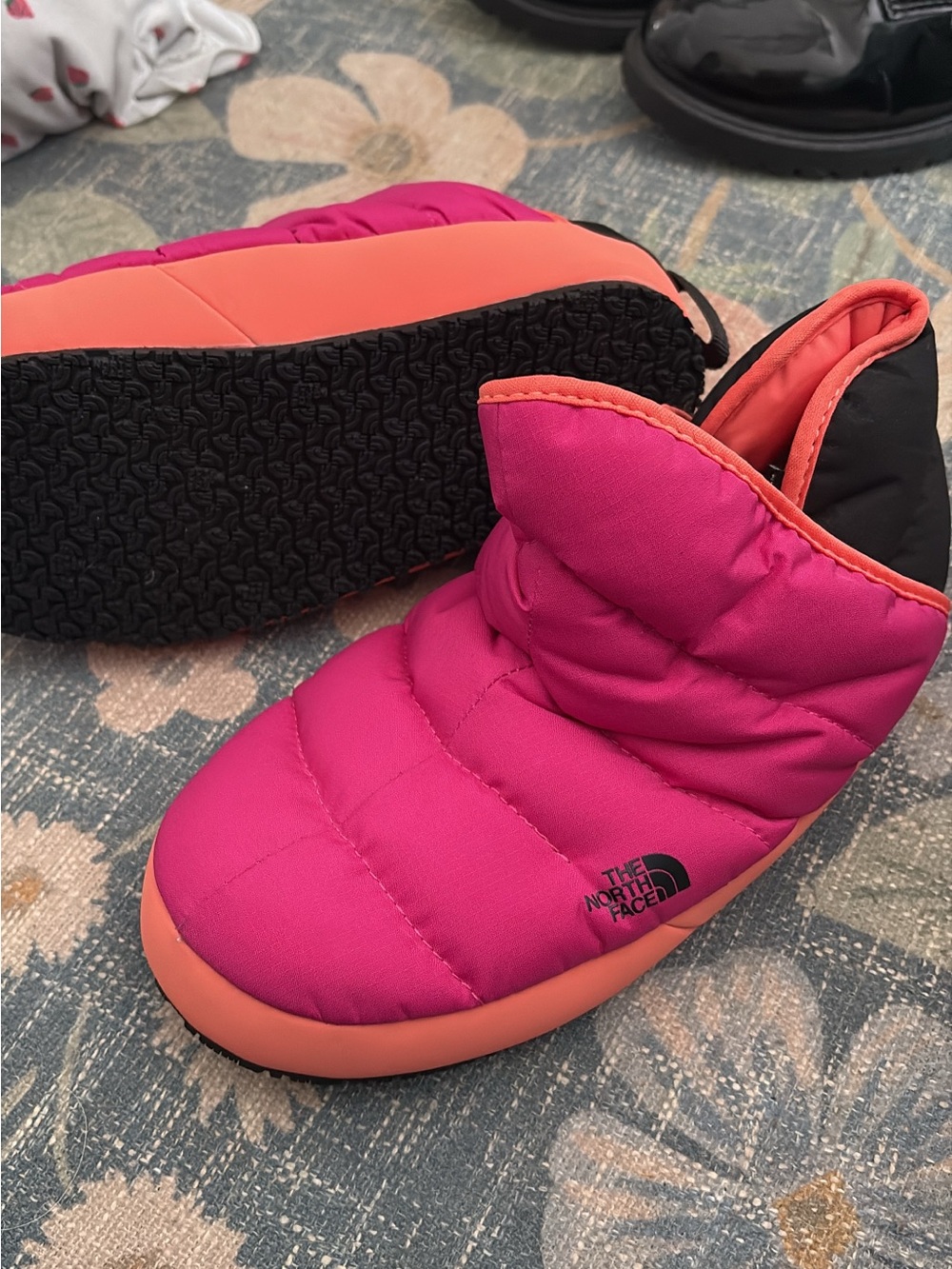 The North Face Kids Pink and Coral Slip-On Puffer Slippers.